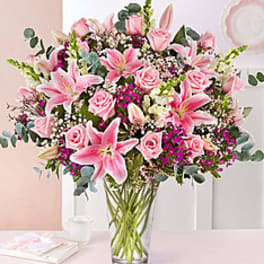 Pink lilies and roses arranged in a clear glass vase