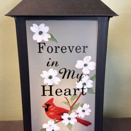 Black lantern with white flowers and a red cardinal reading Forever in My Heart