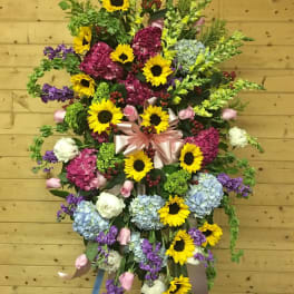 Large standing floral spray with sunflowers, hydrangeas, and ribbon
