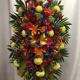Large standing spray with mixed bright flowers and a yellow ribbon