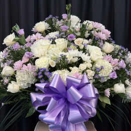 Large lavender and white floral arrangement with a purple ribbon bow