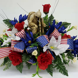Red, white, and blue floral arrangement with patriotic ribbon and a soldier figurine