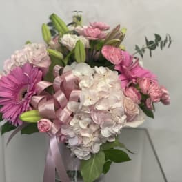 Pink and white bouquet with lilies, hydrangeas, and a ribbon in a vase