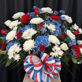 Red, white, and blue floral arrangement with a large ribbon bow