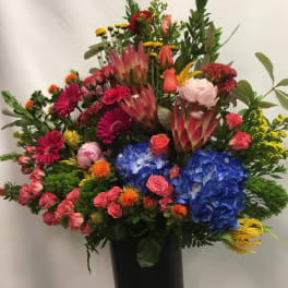 Large mixed bouquet in a black vase with blue hydrangeas and pink roses