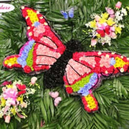Butterfly-shaped floral tribute with colorful flower clusters on a green foliage background