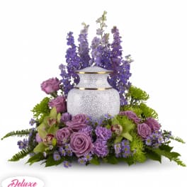 Purple floral arrangement around a white urn vase