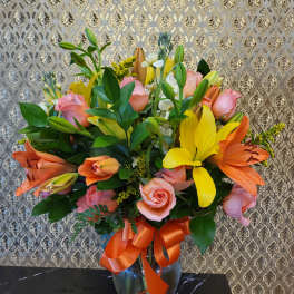 Bouquet of pink roses and lilies in a glass vase with an orange ribbon