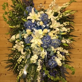 Large standing spray of white lilies and blue hydrangeas with ribbon accents