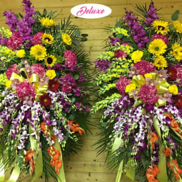 Two large standing floral sprays with yellow, pink, purple, and orange flowers