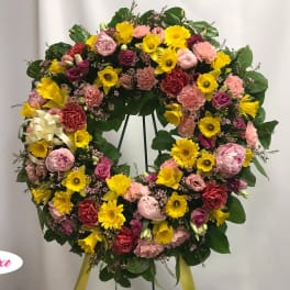 Large circular wreath of pink, yellow, and red flowers on a stand