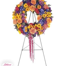 Colorful floral wreath on a standing easel with a pink ribbon tail
