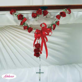 Red rose garland with a large ribbon bow and hanging cross