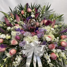 Large floral spray with pink roses, white orchids, and a silver bow