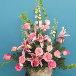 Pink roses, lilies, and carnations arranged in a basket