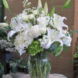White lilies and roses arranged in a clear glass vase