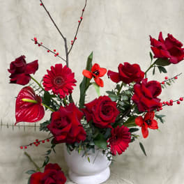 Red roses and gerbera daisies arranged in a white vase