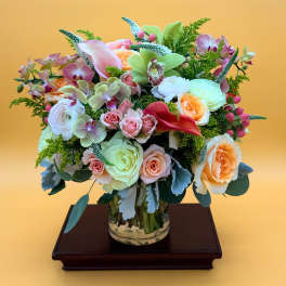 Mixed bouquet of roses, orchids, and calla lilies in a glass vase