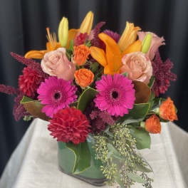 Bright mixed bouquet in a green vase with pink, orange, and red blooms