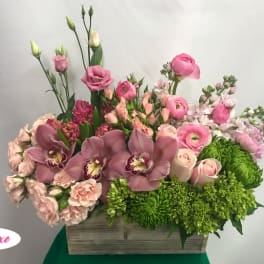 Pink and green mixed flower arrangement in a wooden box