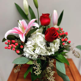 Bouquet of red roses, white hydrangea, and pink lilies in a vase
