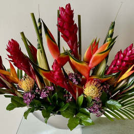 Tropical arrangement with red ginger and orange bird-of-paradise in a white bowl
