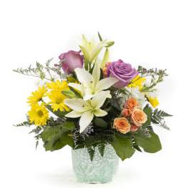 Mixed bouquet with lilies, roses, and yellow daisies in a patterned vase
