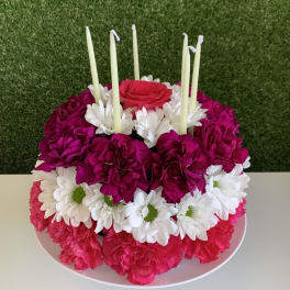 Round floral centerpiece with pink and white flowers and tall candles