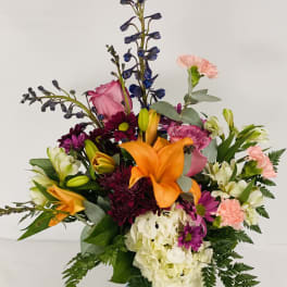 Mixed bouquet in a blue glass vase with orange lilies and pink flowers