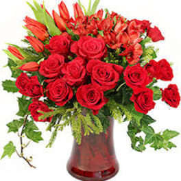 Red roses and orange lilies in a red glass vase