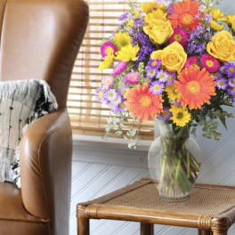 Colorful mixed bouquet in a clear glass vase on a side table