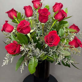 Bouquet of red roses with white filler in a black vase