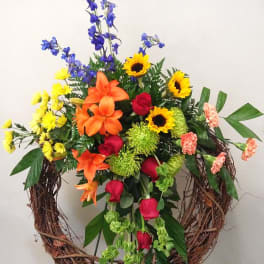 Colorful floral wreath with roses, lilies, sunflowers, and blue delphinium