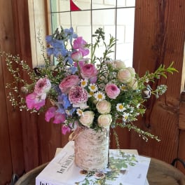 Mixed bouquet in a birch bark vase with pink, white, and blue flowers