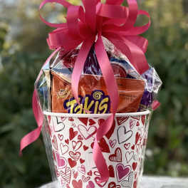 Heart-patterned gift bucket filled with candy and topped with a pink ribbon bow