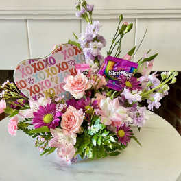 Mixed pink and lavender flower arrangement with candy and a heart-shaped XOXO sign