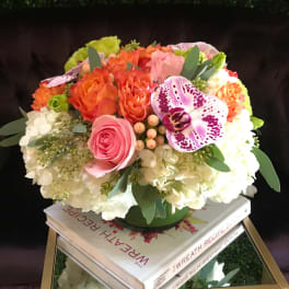 Colorful bouquet with roses, hydrangeas, and an orchid in a low vase