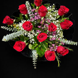 Bouquet of red roses with white filler flowers and greenery on a black background