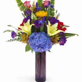 Colorful mixed bouquet in a tall purple glass vase