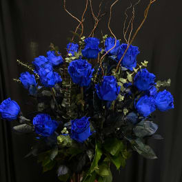 Arrangement of vivid blue roses in a tall vase with curly branches