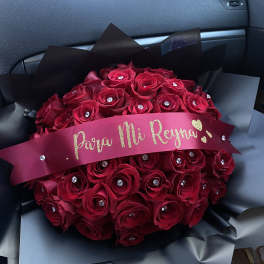 Bouquet of red roses wrapped in black paper with a pink ribbon