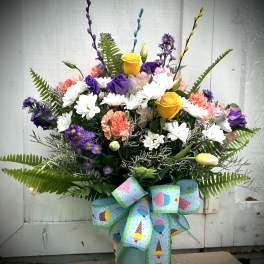 Mixed bouquet in a blue vase with a large patterned ribbon
