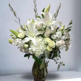 White lilies and roses arranged in a glass vase