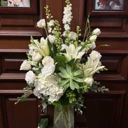 White floral arrangement in a clear glass vase with lilies and hydrangeas