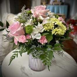 Pink roses and mixed flowers arranged in a clear glass vase