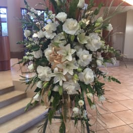 Tall white floral standing arrangement on an easel with ribbon