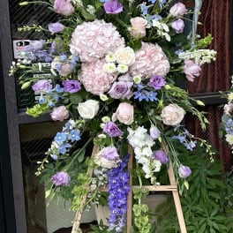 Tall floral standing arrangement with pastel roses, hydrangeas, and delphinium