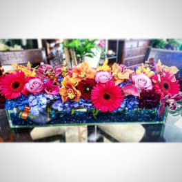 Bright mixed flower arrangement in a rectangular glass vase