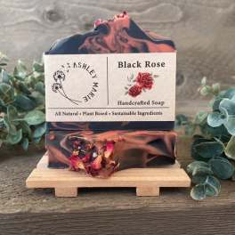 Two bars of black and pink rose soap on a small wooden stand