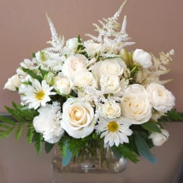 White roses and daisies arranged in a clear glass vase